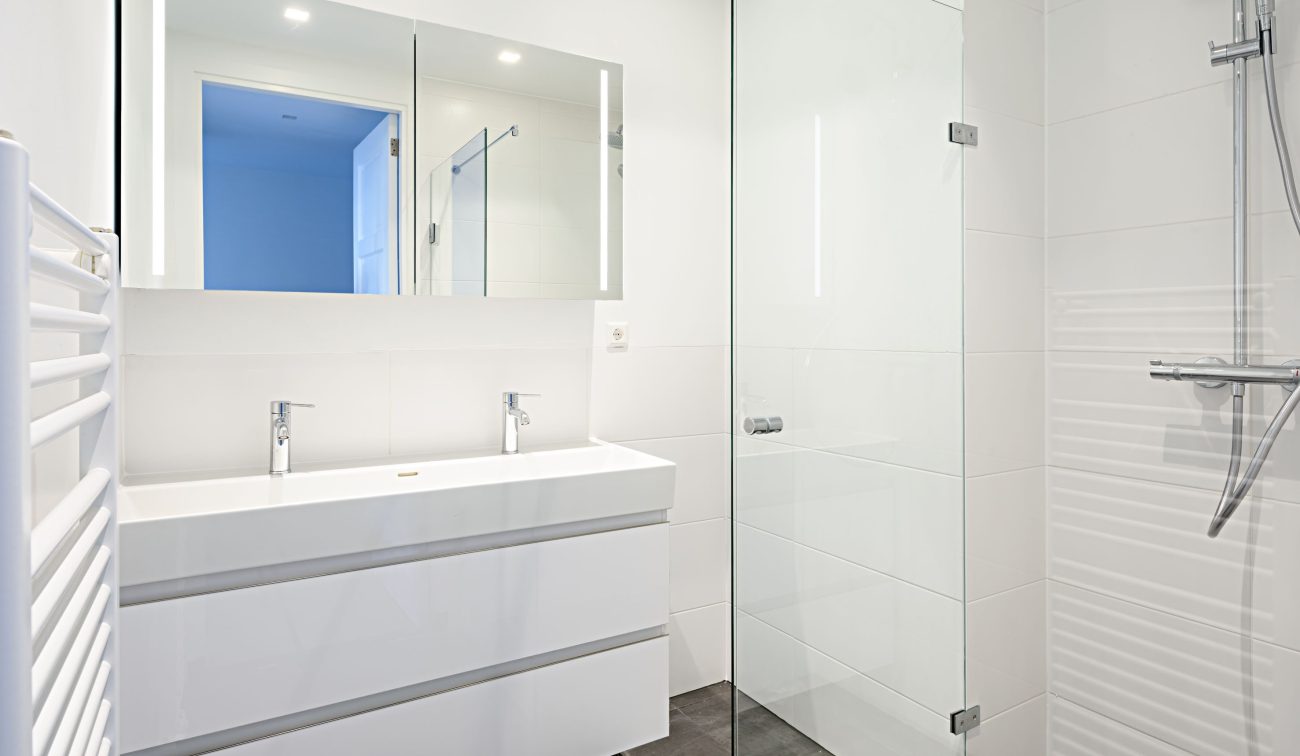 Moderne badkamer Ruysdaelstraat: inloopdouche met glas, dubbele kraan en donkergrijze vloertegels