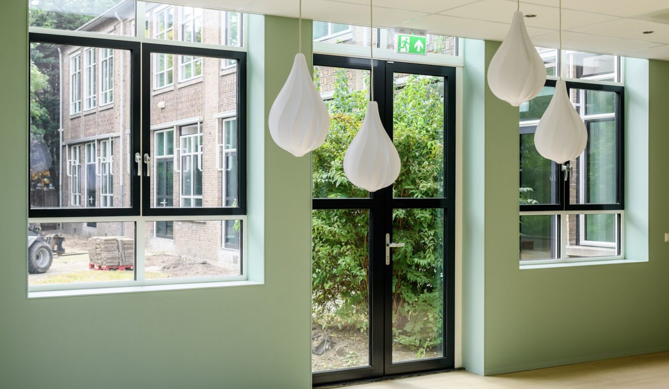 Interieur De Fakkel Utrecht: grote ramen, zwarte profielen, mintgroene nis en organische lampen