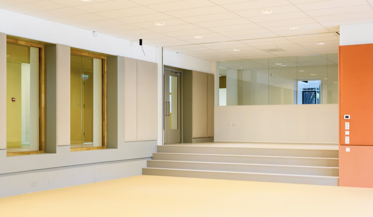 Schoolinterieur De Fakkel: ruime leerpleinzone met trappartij, dempingspanelen en frisse kleuren