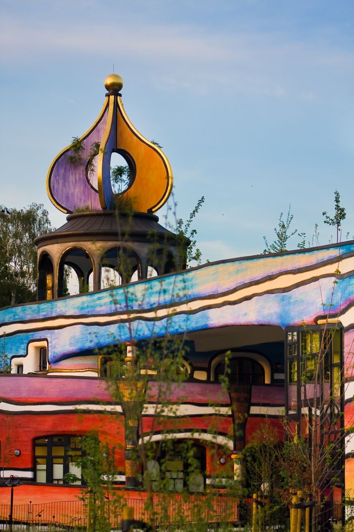 Ronald McDonald Kindervallei Valkenburg met goudkleurige ui-koepel en golvend blauw dak boven de kleurrijke, organische gevel