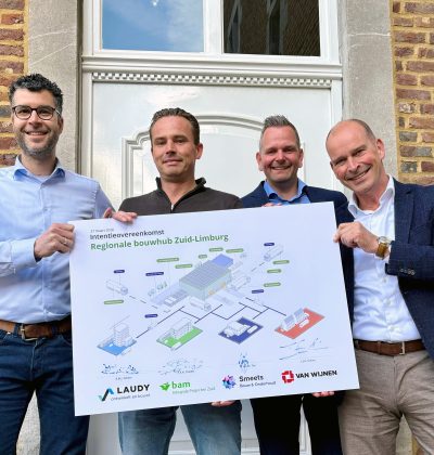 Vier mannen houden een bord omhoog en lachen naar de camera