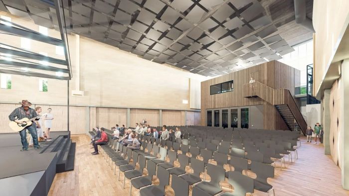 Impressie van multifunctionele zaal met podium, stoelenopstelling en publiek tijdens muzikale uitvoering.