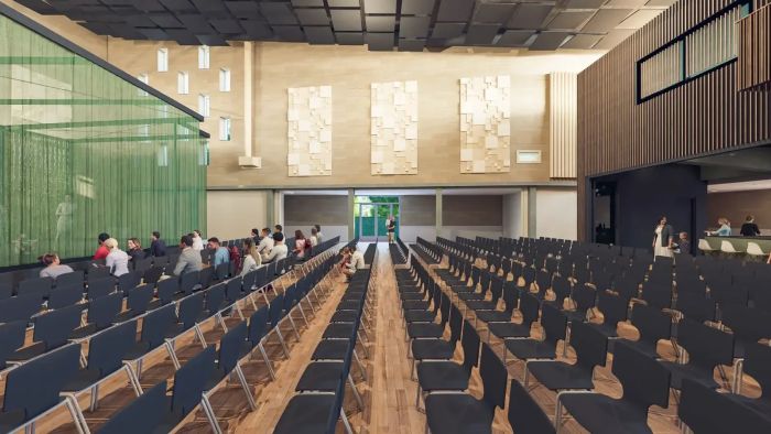 Interieurimpressie van multifunctionele zaal met stoelenopstelling, bezoekers en akoestische panelen.