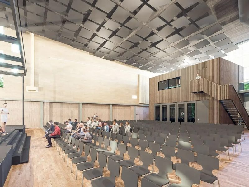 Impressie van multifunctionele zaal met podium, stoelenopstelling en publiek tijdens muzikale uitvoering.