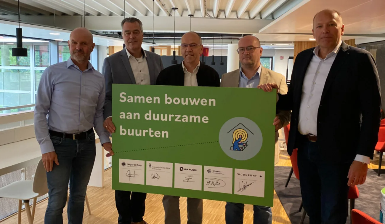 Vijf mannen houden bord met tekst Samen bouwen aan duurzame buurten en handtekeningen
