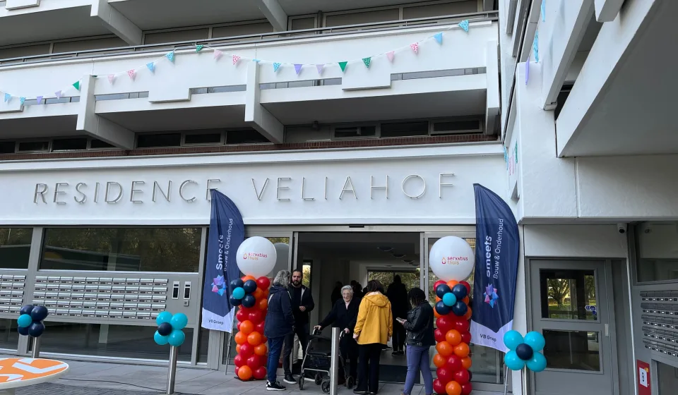 Entree van Residence Veliahof met ballonnen, vlaggen en bezoekers bij de ingang