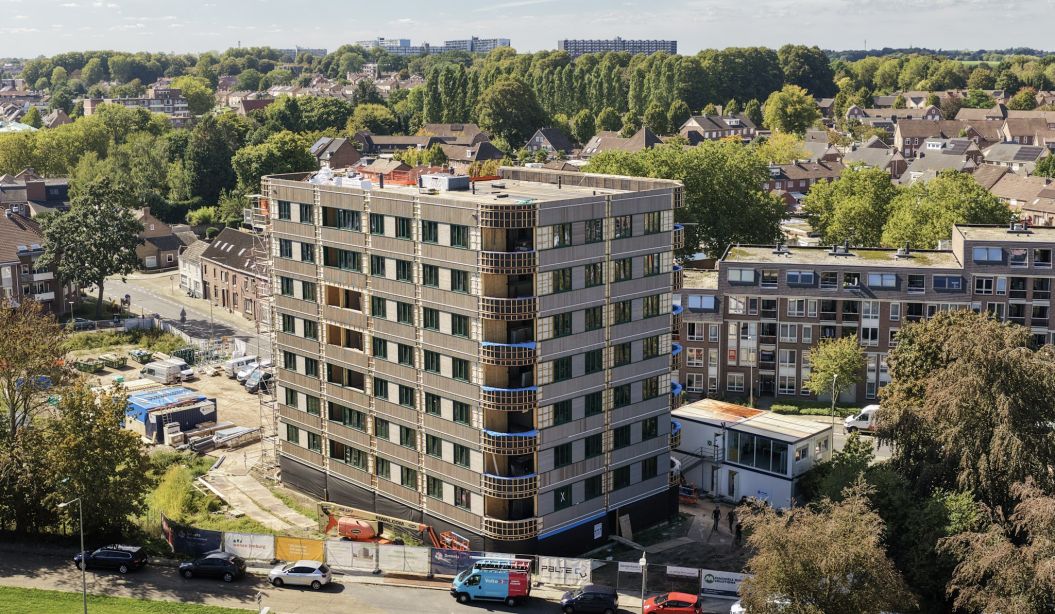 Appartementengebouw met balkons en omliggende woonwijk vanuit vogelperspectief