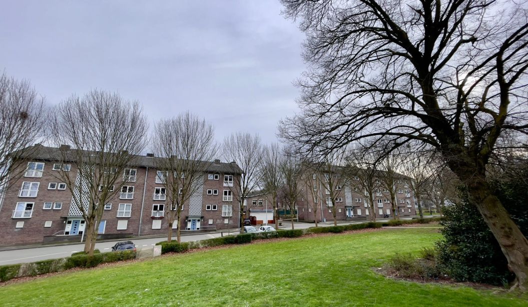 Maastrichtse portiekwoningen langs straat, zicht vanaf grasveld – project verduurzaming 91 woningen.