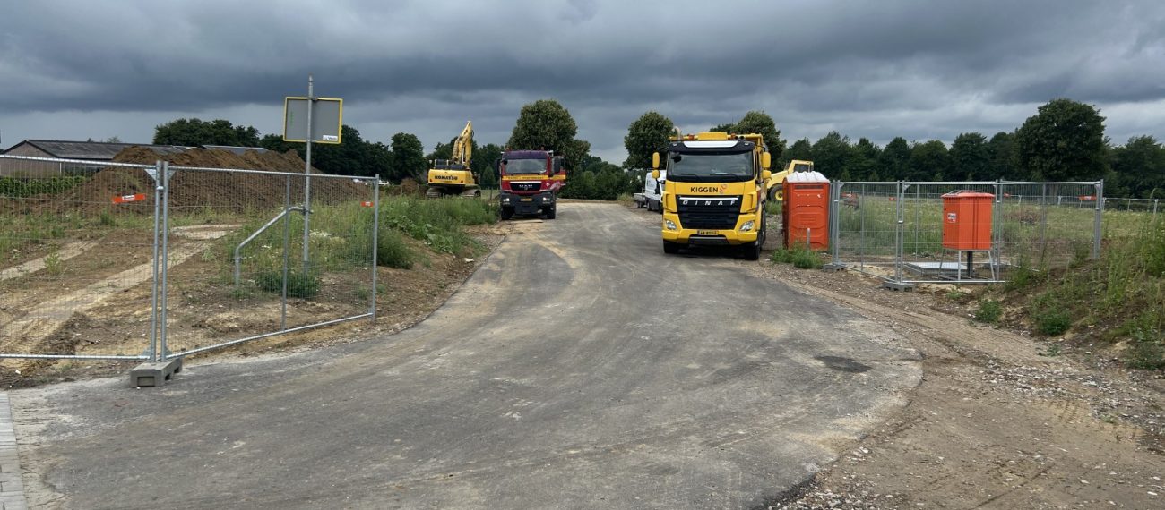 twee vrachtwagens en in de verte een graafmachine op een bouwplaats