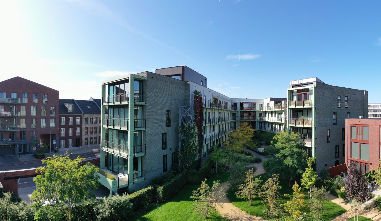 CPO Sphinx Maastricht – panorama van binnenhof met groene tuin, paden en moderne woonblokken in baksteen en groen beton