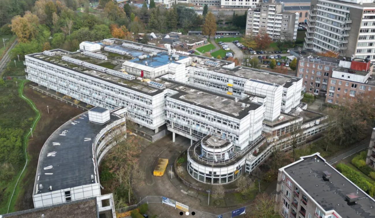 Kloosterbeemden Kerkrade – luchtfoto van groot wit gebouwcomplex met terrassen en ronde entree, omgeven door woonblokken en groen