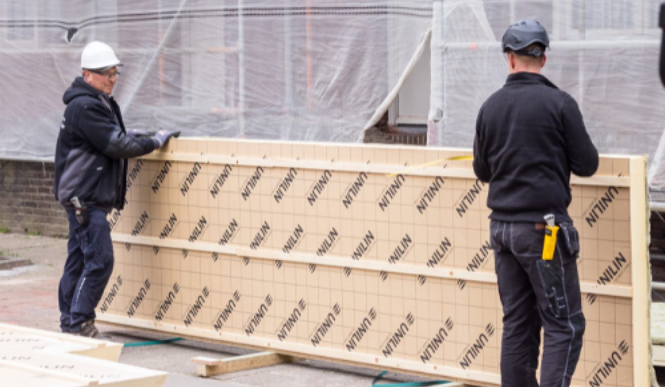 Monteurs verplaatsen geïsoleerde UNILIN panelen bij renovatie 91 woningen Maastricht.