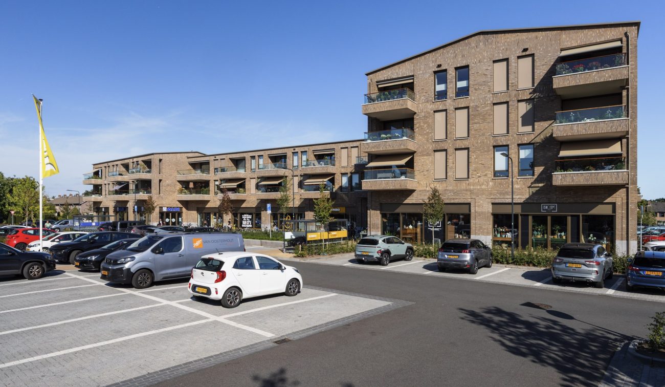 Nieuwbouw De Scheperij Teteringen: woonwinkelblok met balkons baksteen en parkeren op voorplein ruim