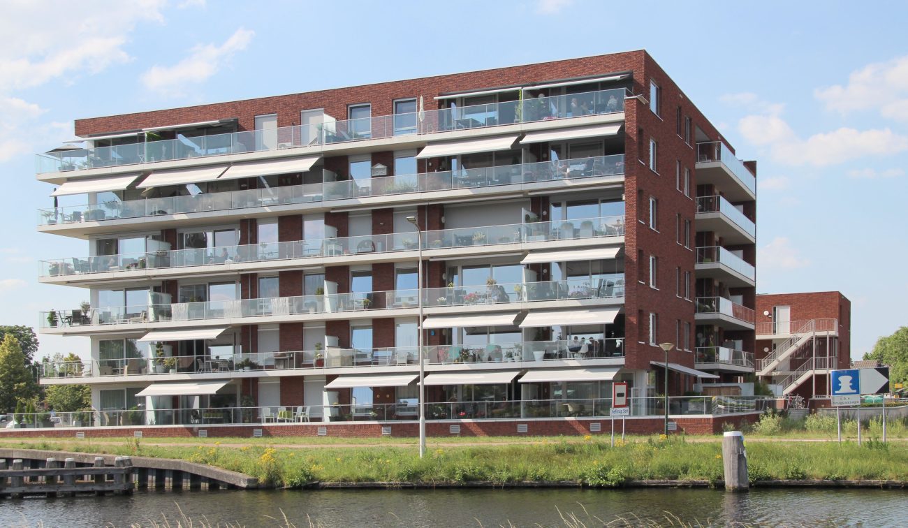 Nieuwbouwcomplex op het HIVA-terrein in Son, gezien vanaf het water, met zicht op de moderne architectuur en de waterkant.