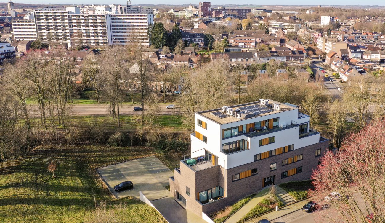 Modern woonvolume in witte stuclaag en donkere baksteen, verhoogd gelegen met uitzicht op wijk — Gebiedsontwikkeling Parkheuvel Heerlen