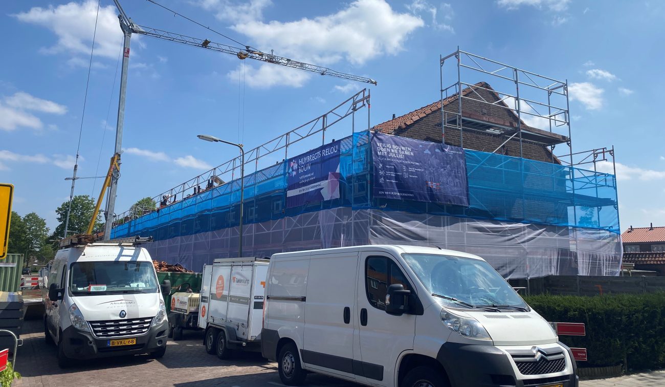 Straatbeeld van de Rootstraat in Oss met woningen in steigers en onderhoudsbusjes aanwezig tijdens de uitvoering van het groot onderhoudsproject.