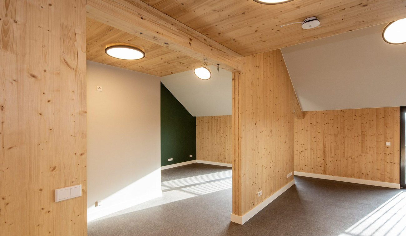 Interieur van een nieuwbouwappartement in woonzorgcomplex Pontenage in Gemert, met houten wanden en plafonds, moderne verlichting en een schuine dakconstructie.