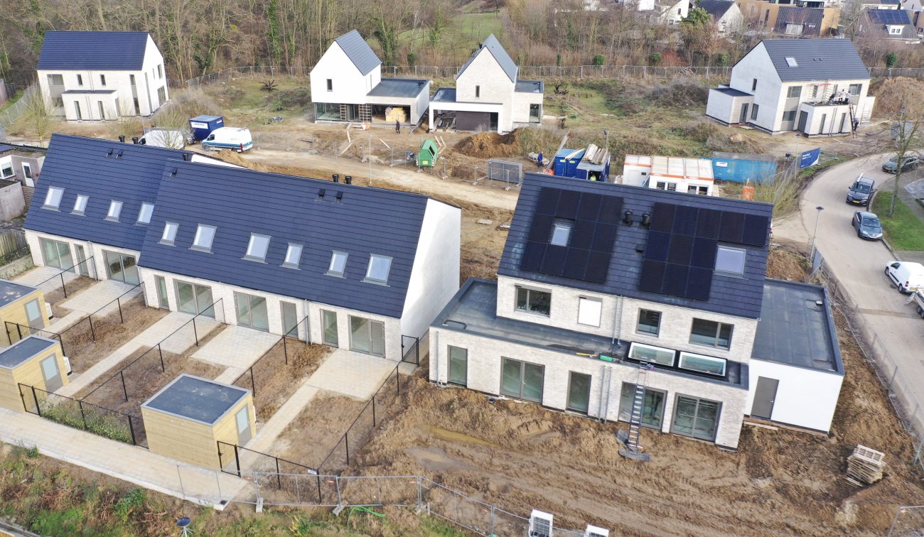 CPO Meerdel Elsloo – luchtfoto van rij- en tweelaagse woningen met donker zadeldak en zonnepanelen, tuinen met terrassen en hekwerk in aanleg