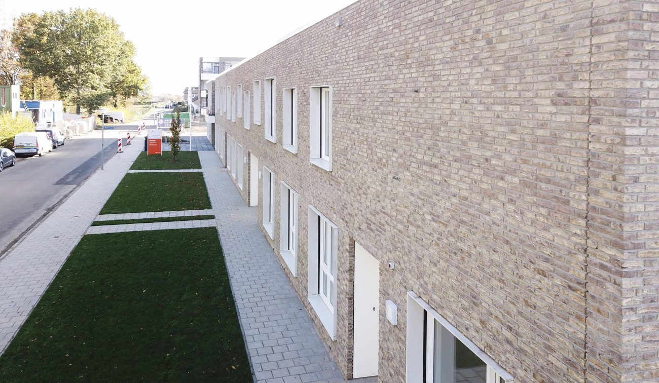 Zijgevel verpleeghuis Panhuys Hulsberg met lichte baksteen en stroken groen.