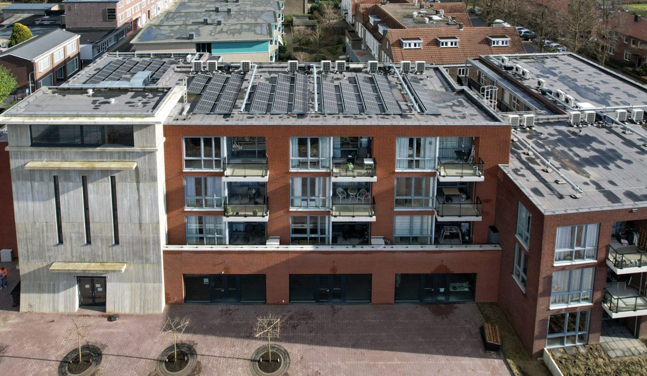MFA Hart voor Treebeek Brunssum – luchtfoto van rood bakstenen gebouw met balkons en plat dak vol zonnepanelen