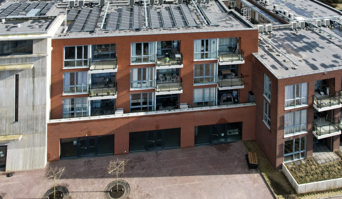 MFA Hart voor Treebeek Brunssum – bakstenen gevel met glazen balkons naast betonnen toren, plint met entrees en ramen