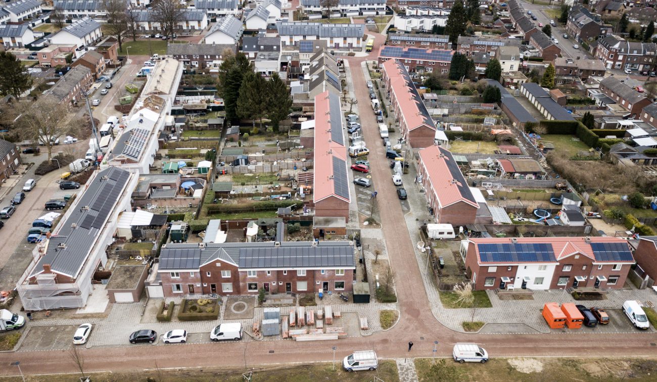 Overzicht woonwijk Heilust, renovatieblokken met rode dakpannen, PV-panelen en bouwbussen.
