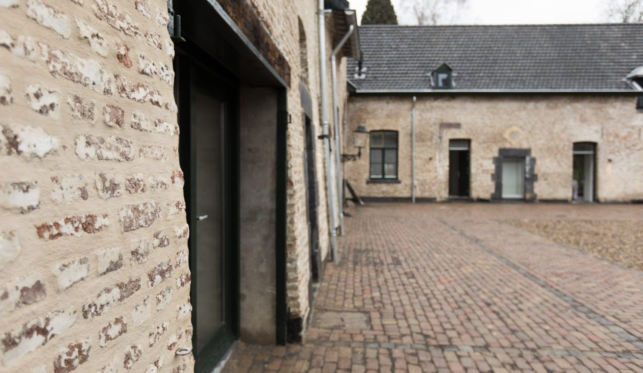 Binnenhof met kasseien en mergelstenen gevels van carréhoeve — herbestemming tot appartementen Maastricht.