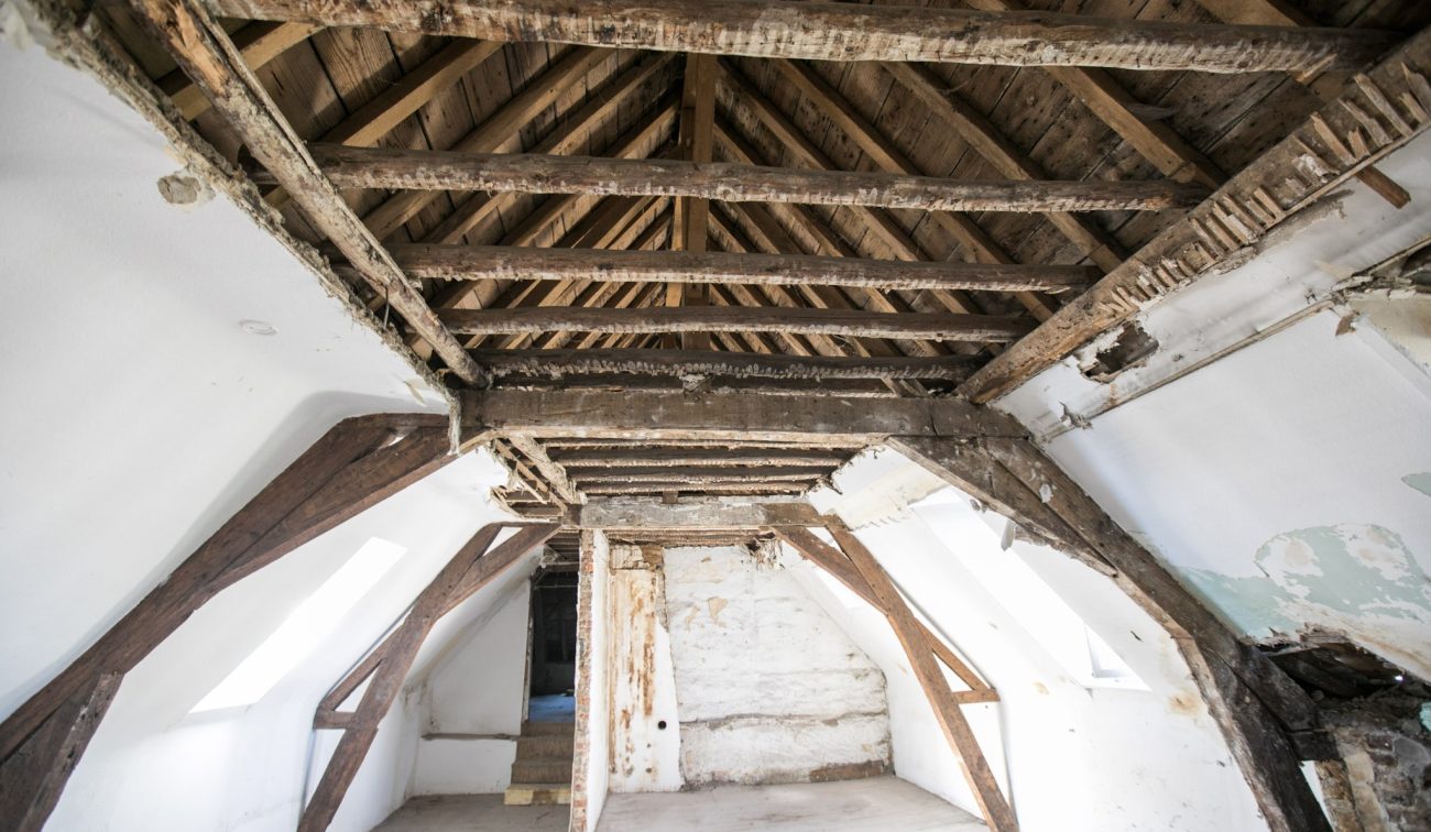 Zolder met zichtbare eiken spanten en gebinten in oude hoeve — herbestemming tot appartementen Maastricht