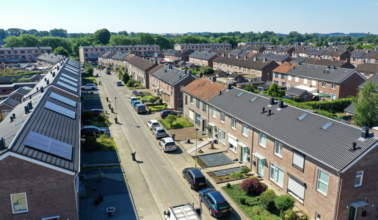 Perspectief door woonwijk met bakstenen rijtjeshuizen, voortuinen en stoepen — Groot onderhoud 154 woningen Nieuwdorp Stein