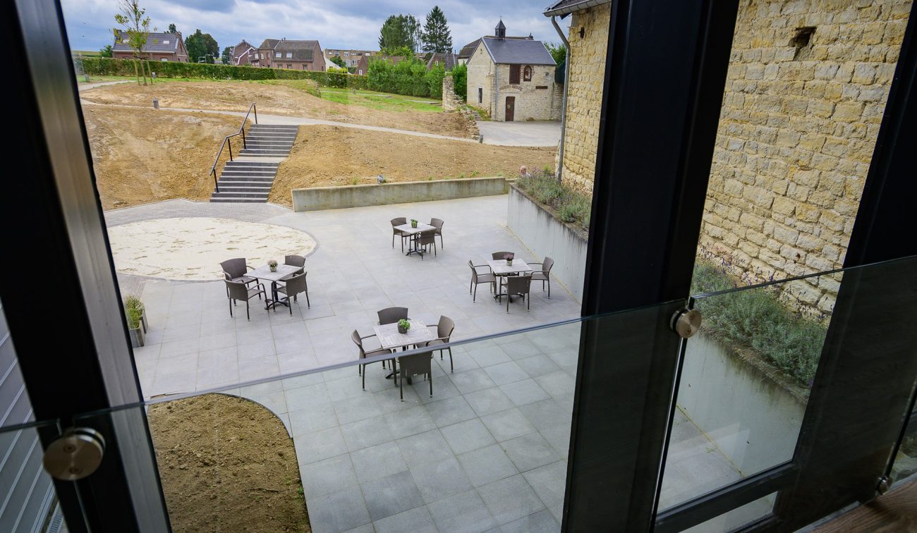 Verzonken buitenterras Hoeve Overhuizen met tafels, omgeven door mergelstenen muren.