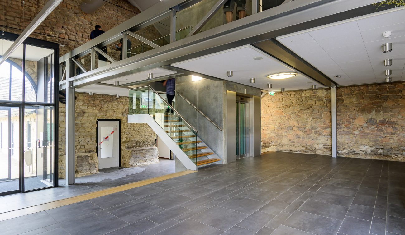 Entreehal Hoeve Overhuizen met stalen mezzanine, glazen trap en lift in natuursteen