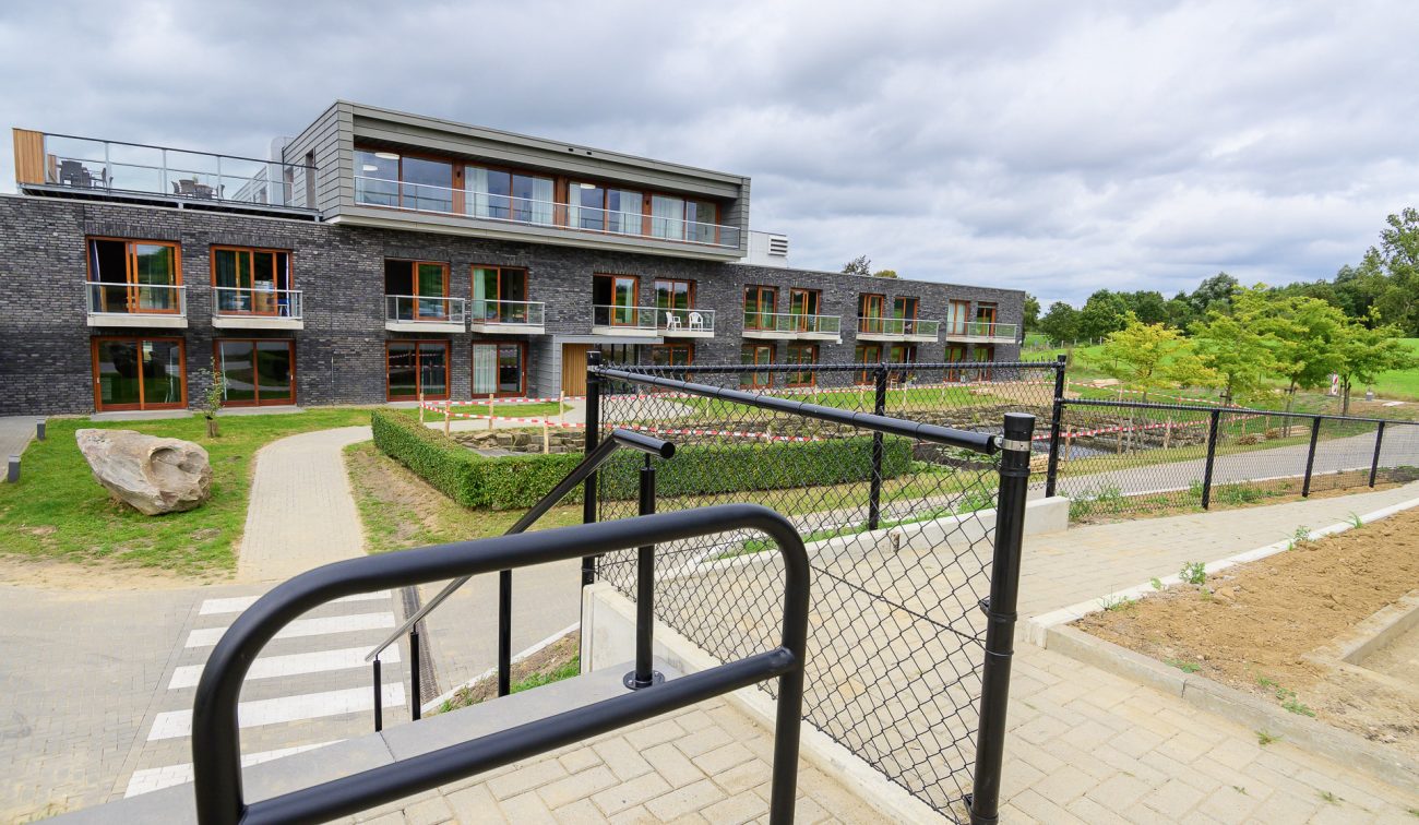 Modern woongebouw met houten kozijnen, balkons en gemeenschappelijke binnentuin met hekwerk.