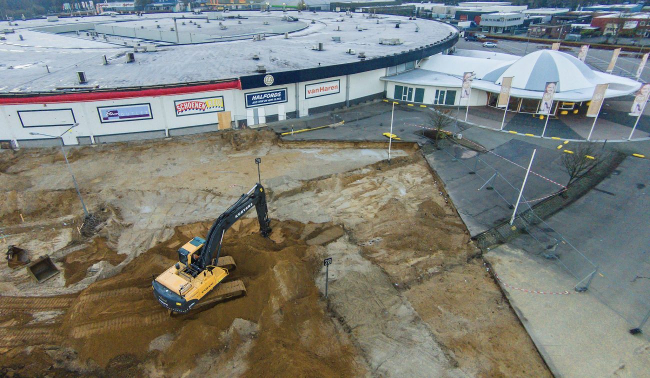 Luchtfoto uitbreiding Makado Beek: graafwerk naast rond winkelcentrum met koepelentree.
