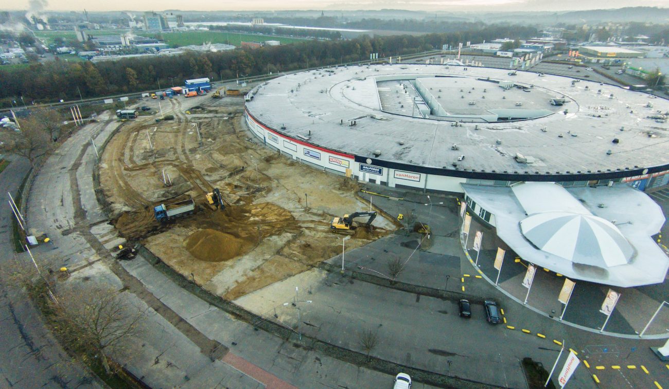 Luchtfoto uitbreiding Makado Beek: graafwerk naast rond winkelcentrum met koepelentree.