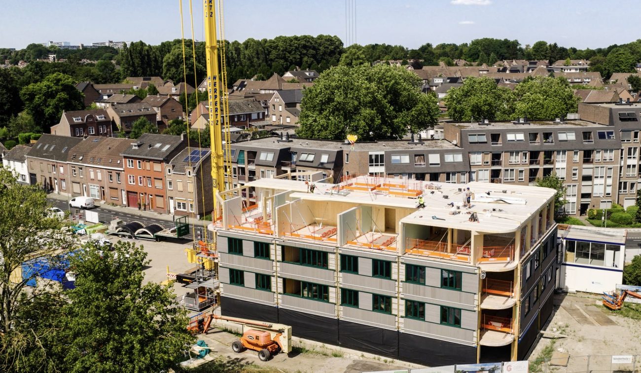 Appartementengebouw in aanbouw met hijskraan en prefab gevelelementen op bouwplaats