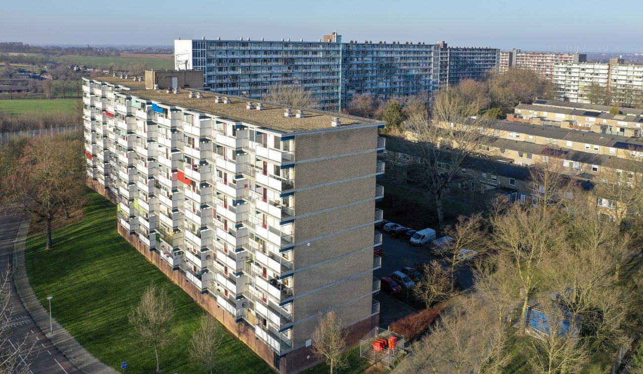 Luchtfoto galerijflat op groen talud met balkons en parkeerterrein — Groot onderhoud Albert Schweitzer Brunssum