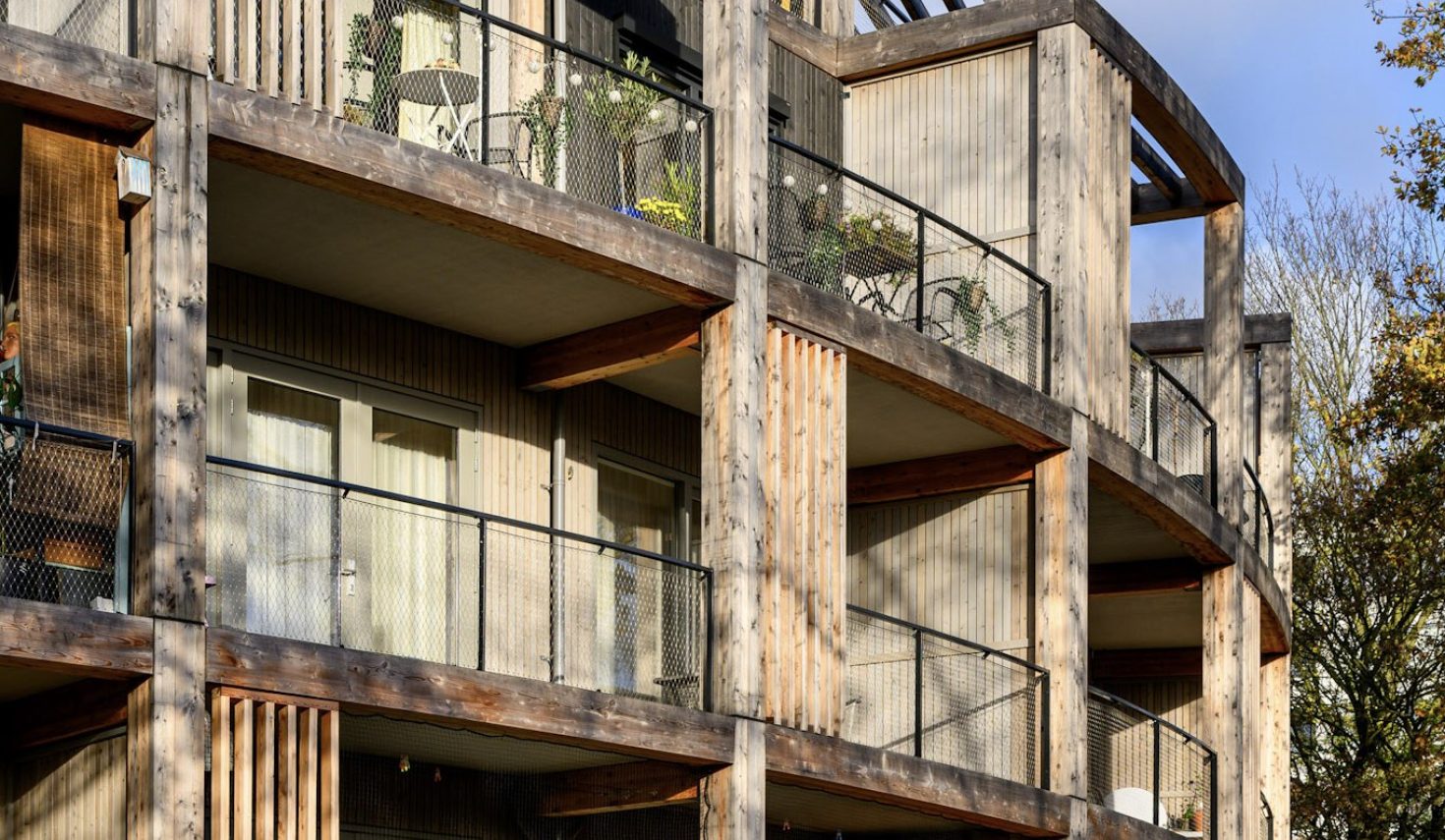 Nieuwbouw ROOT Eindhoven – duurzame houten gevel met ronde balkons en moderne natuurinclusieve architectuur.