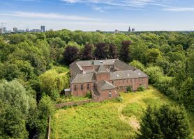Landgoed met bakstenen gebouw midden in bosrijk landschap vanuit vogelperspectief