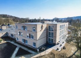 Zorgcomplex Valkenburg, moderne blok met lichte baksteen, paden en terrassen aan gevel.