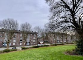 Maastrichtse portiekwoningen langs straat, zicht vanaf grasveld – project verduurzaming 91 woningen.