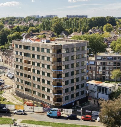 Appartementengebouw met balkons en omliggende woonwijk vanuit vogelperspectief