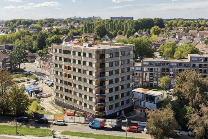 Appartementengebouw met balkons en omliggende woonwijk vanuit vogelperspectief