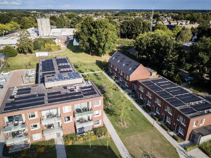 Luchtfoto van de nieuwbouw van NOM-woningen in Vogelsanck, Gemert, met energiezuinige appartementen en rijtjeswoningen in een groene wijk.