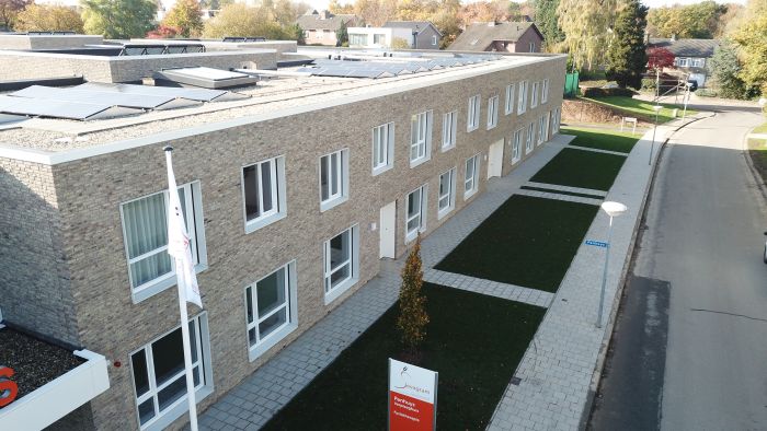 Straatzijde verpleeghuis Panhuys Hulsberg met lichte baksteen, ramen en groenstroken.