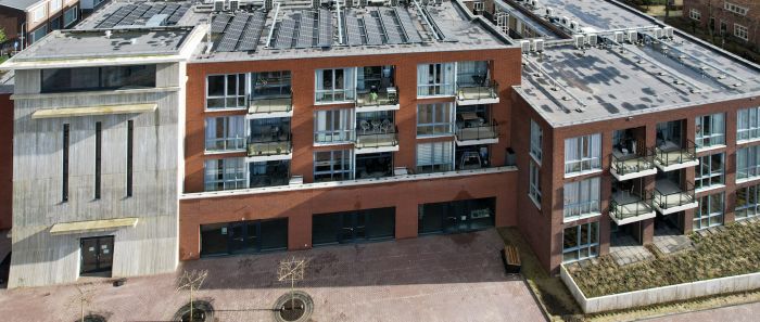 MFA Hart voor Treebeek Brunssum – rood-bakstenen gevel met glazen balkons naast markante betonnen toren, plint met entrees