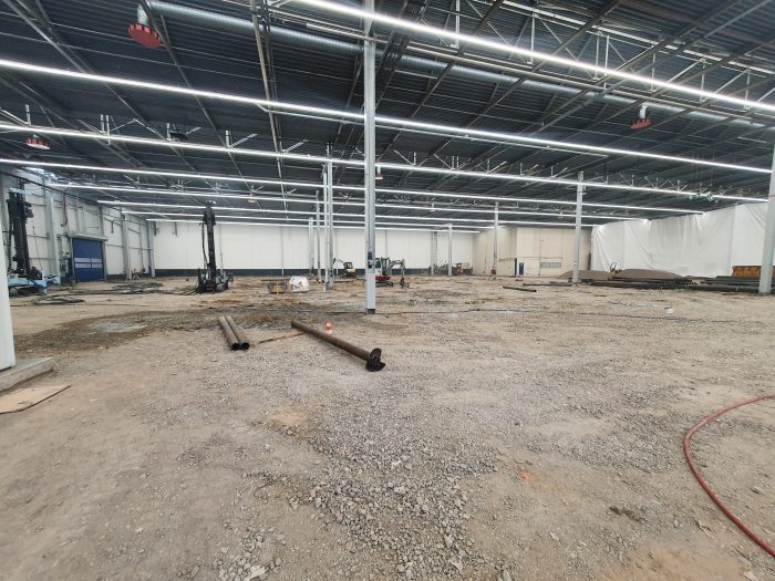 Renovatie van de betonvloer in hal A50 bij DAF Eindhoven, met opengebroken vloer, bouwmaterieel en voorbereidende werkzaamheden in de fabriekshal.